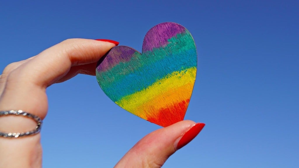 Hand holding rainbow coloured heart