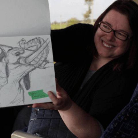Dr. Linda Carson smiling and holding a sketchbook