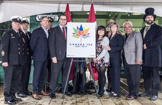 Ariana Cuvin is shown standing next to her winning logo design in an unveiling ceremony in Burnaby, B.C.