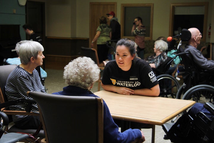 Young woman sitting at a table talking with others