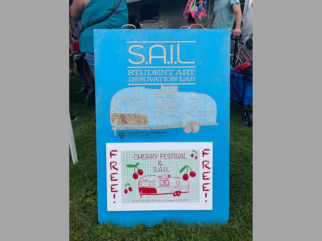 A sandwich board advertises SAIL Student Art Innovation Lab and the free event at the Cherry Festival.