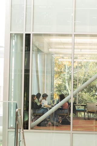 Students in QNC sitting at a desk and studying, glass wall.