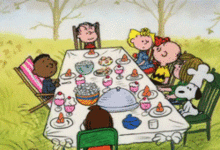 Video of Charlie Brown surrounded by friends at a dinner table.