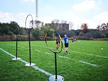 Quidditch players practicing with three hoops on the field.