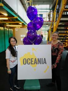 Quunn Nguyen and Erika Tan beside a sign that says &quot;Oceania&quot;.