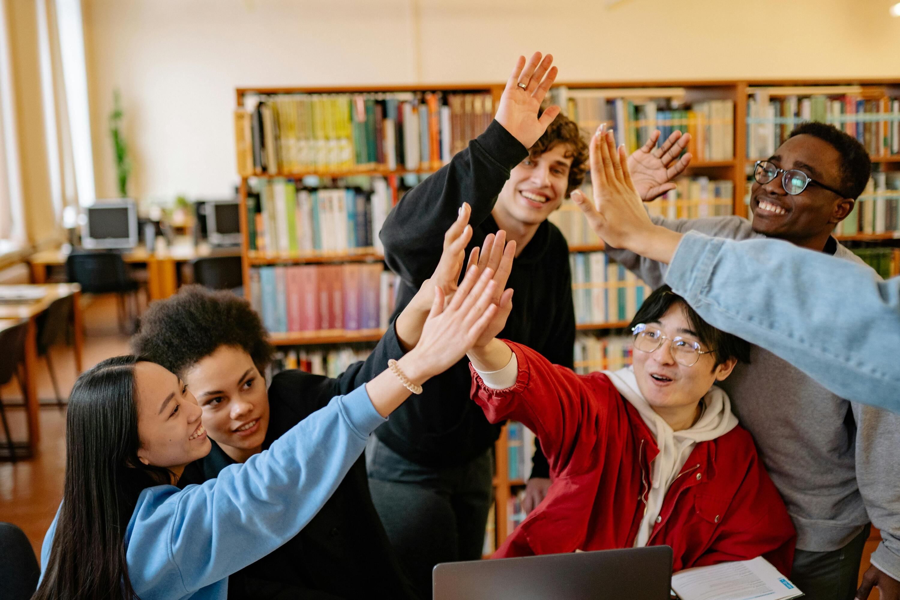 a group of people high five-ing in a library
