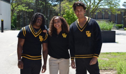 Three students wearing new WStore merchandise and posing for the camera on campus