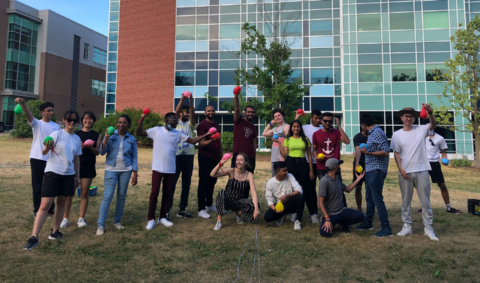 International students holding water balloons and posing for the camera during an International Peer Community event