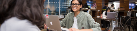 Student sitting in lounge study area in South Campus Hall with a laptop 