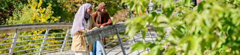 two students standing on a bridge looking out at the view