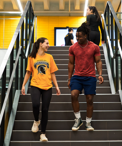 Two students walking down a staircase at the Physical Activities Complex