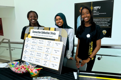 Three students at a Connection Collective booth on campus
