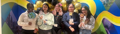 Students standing in the main entrance of the International Experience Centre holding up photo booth props
