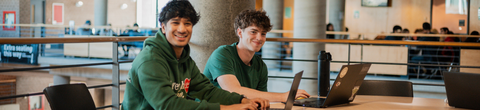Two students sitting together at a meeting table on the 2nd floor of SLC.