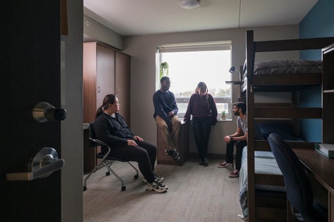 Photo of United College double room with bunk beds. 3 students sit in the room