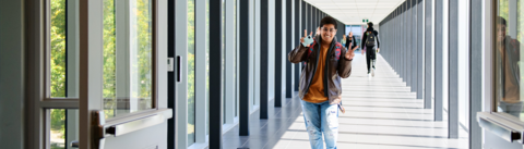 student walking through campus giving the peace sign