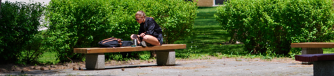 student sitting on bench doing work 