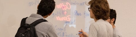Three people staring at a whiteboard