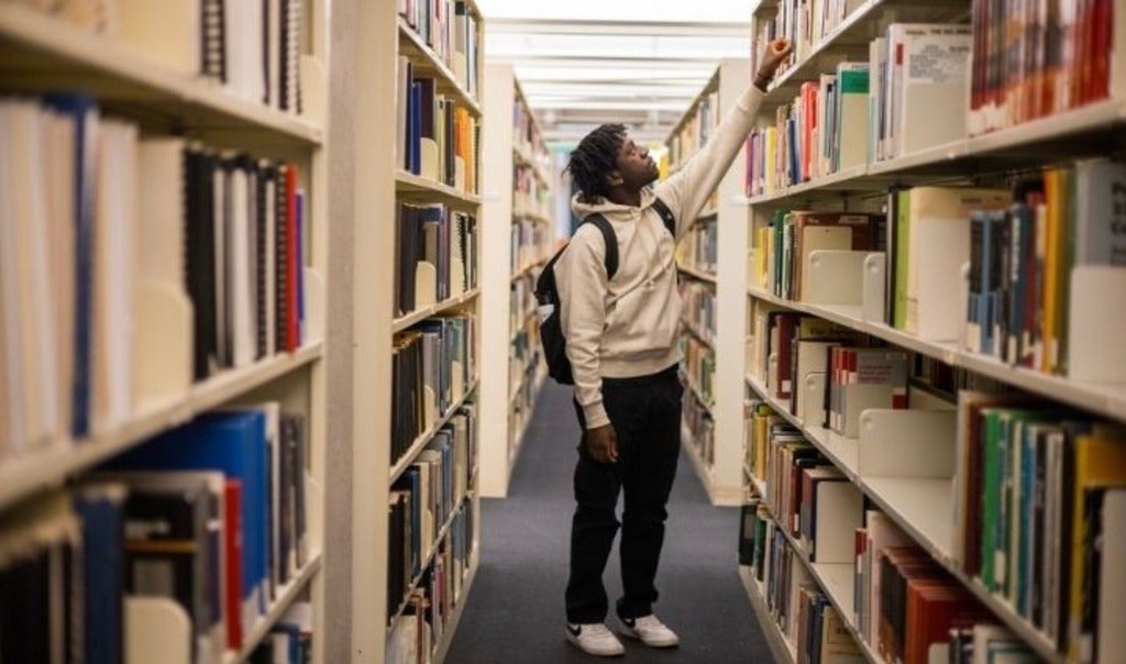 Student grabbing a book from a bookshelf