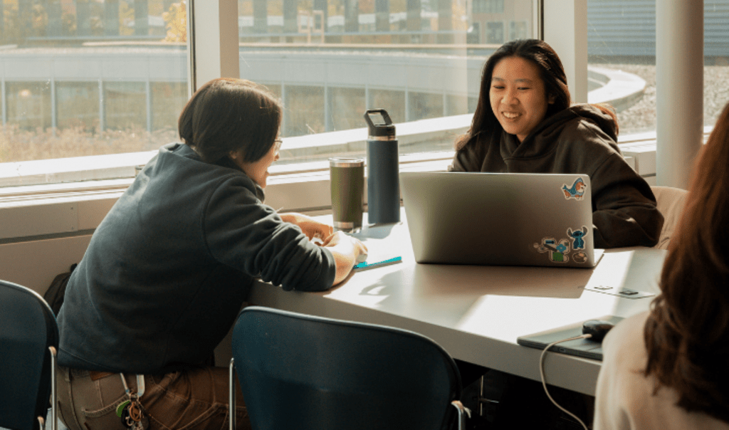 Two students working together at a shared table in the Student Life Centre
