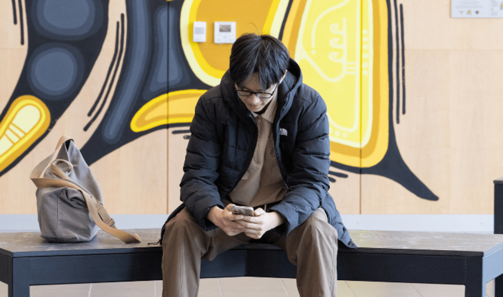 Student sitting with their head down looking at their phone