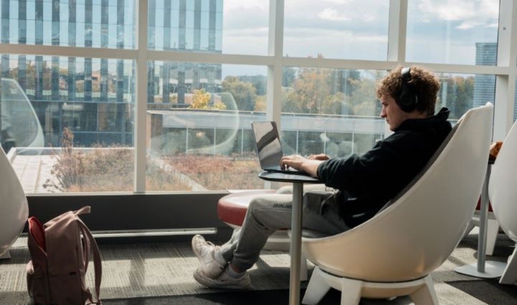 Student typing on laptop with headphones on