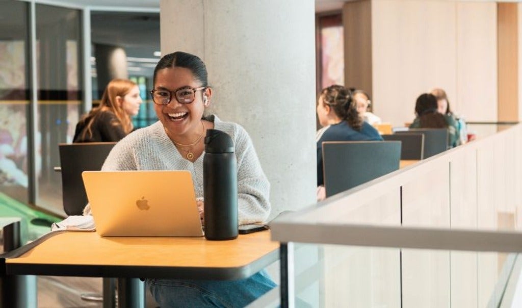 Student sitting with their laptop smiling