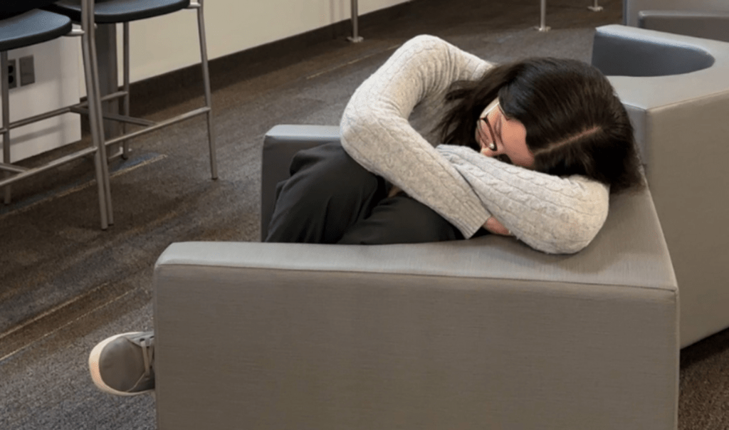 Student curled up and sleeping in a chair on campus