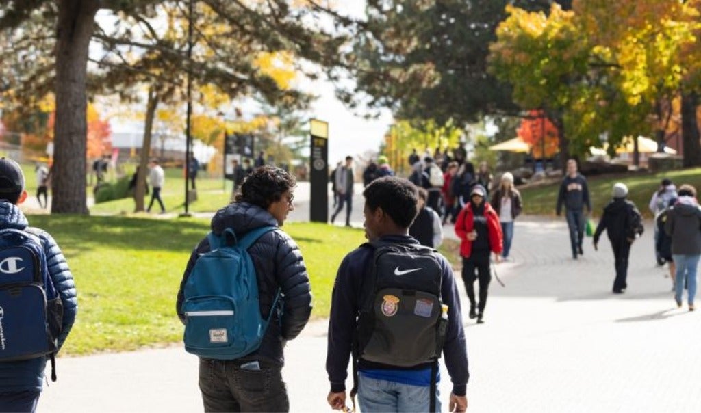 Student walking on the main Two Row path in fall.