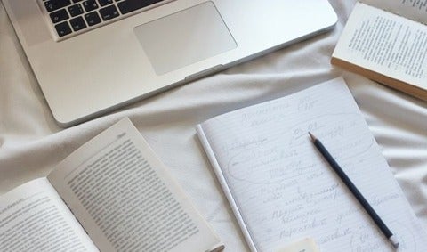 A note book, a text book, and a laptop on a table. 