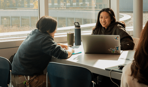 Two students working together at a shared table in the Student Life Centre