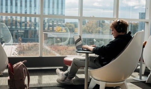 Student typing on laptop with headphones on
