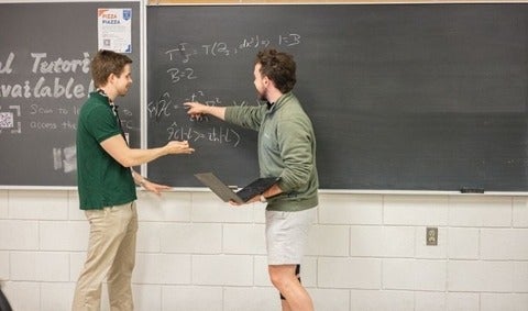 Student and teaching assistant working out a problem on the chalkboard