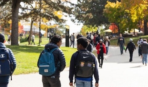 Student walking on the main Two Row path in fall.
