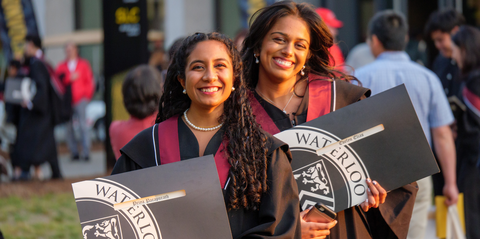 two ladies at comvocation holding up their degrees