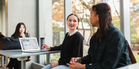 People sitting and talking at a desk in front of a window