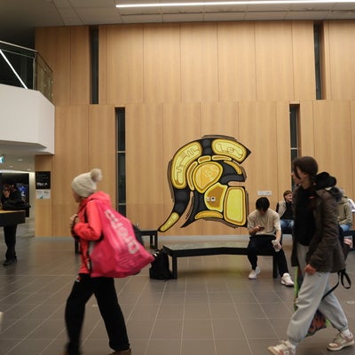 Indigenous Warriors logo on display in the PAC with students passing by