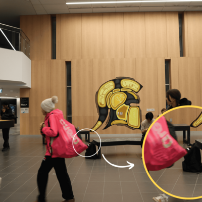 The goose is inside the black backpack placed beside the bench