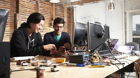 2 male students work with gadgets on a work desk