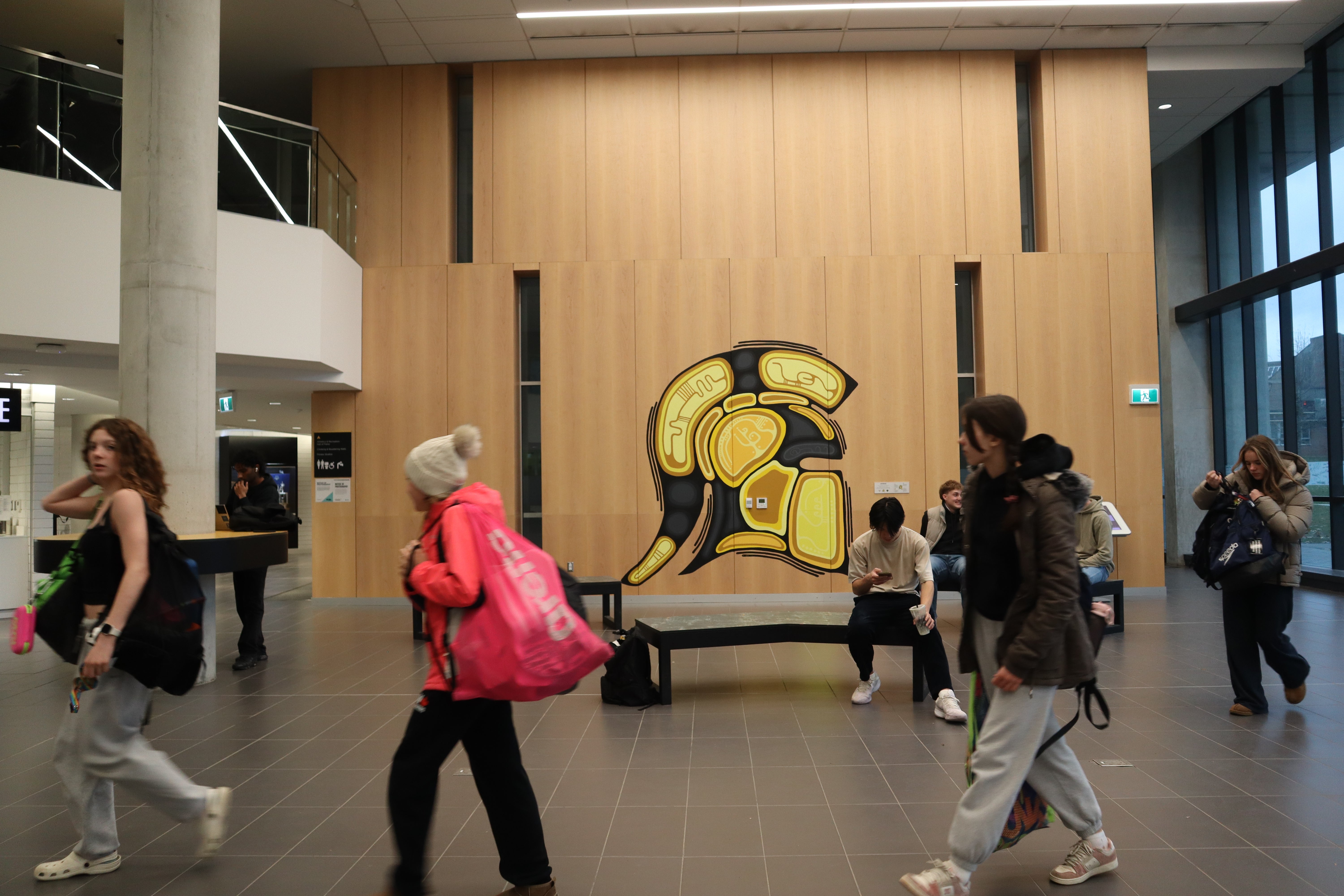 Indigenous Warriors logo on display in the PAC with students passing by