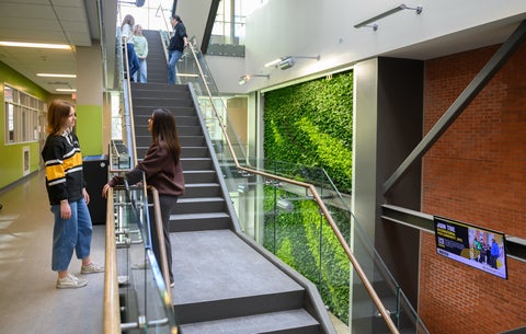 two students talk on the stairs in the Environment 3 building