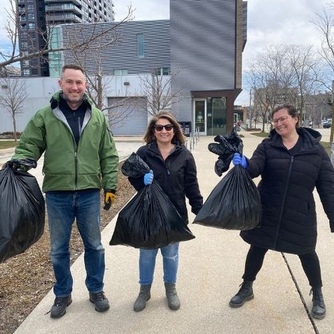 Three employees cleaning up sidewalk by School of Pharmacy