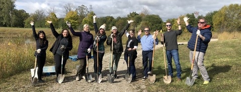 Group of people holding shovels with their hands in the air