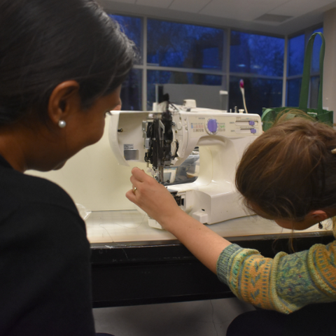 Two people repairing a sewing machine at repair workshop