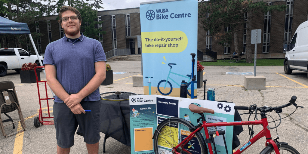 Volunteer in front of WUSA Bike Centre sign at Bike Fair 2023