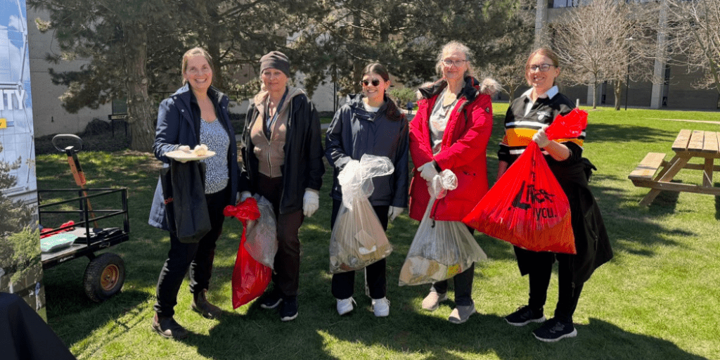 5 people holding up bags of litter they collected.