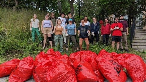 Volunteers smile in front of bags of invasive species they removed 