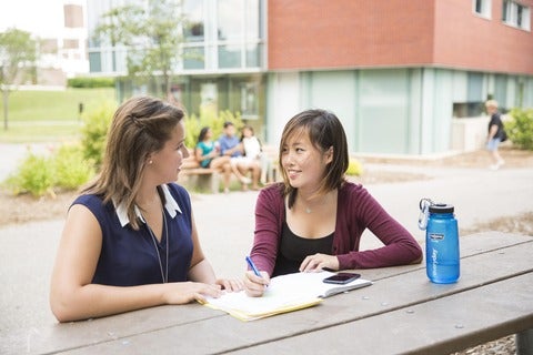 Two students at a picnic table in DP quad area