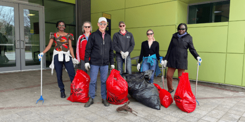 6 employees in front of EV3 with garbage bags at 2023 campus clean up
