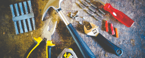 Repair tools laid on table, including hammer, pliers, screwdriver and tape measure